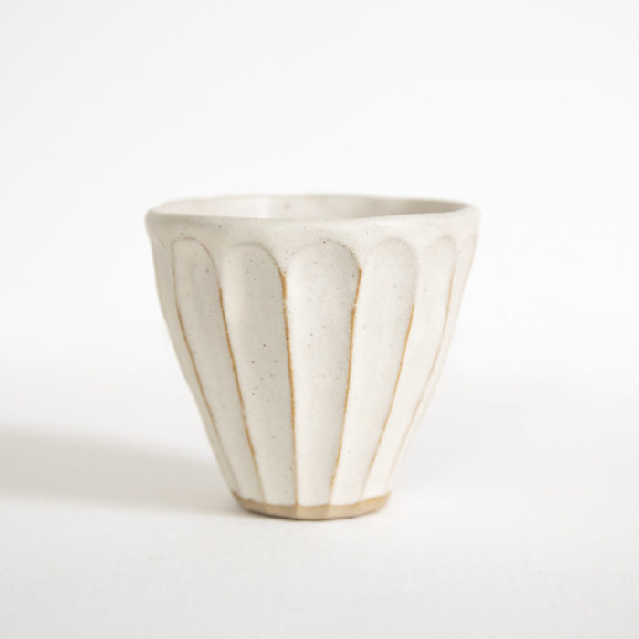 A small white ceramic cup on a white surface.