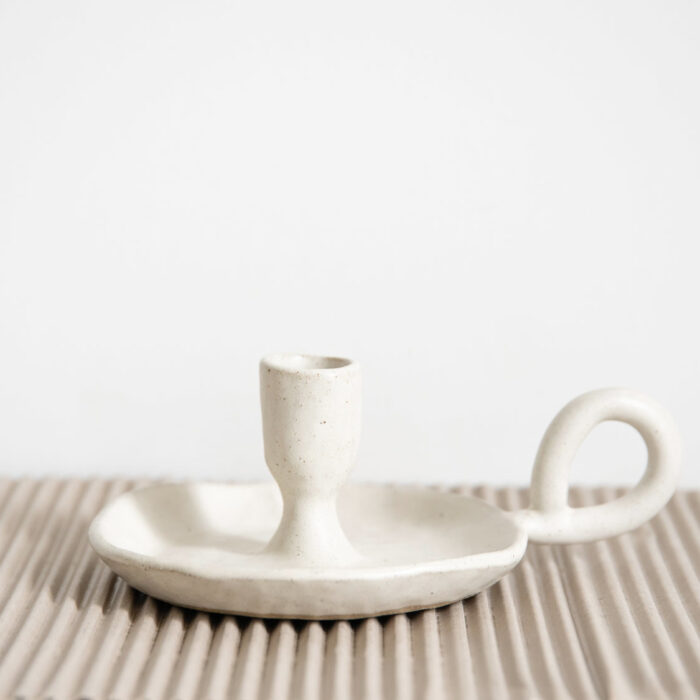 A small white candle holder on top of a mat.
