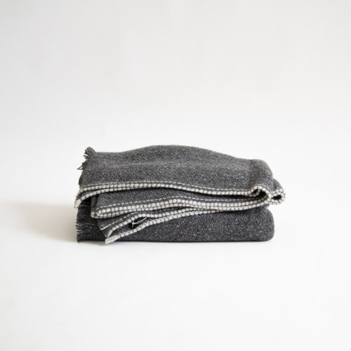 A grey blanket folded on top of a white background.