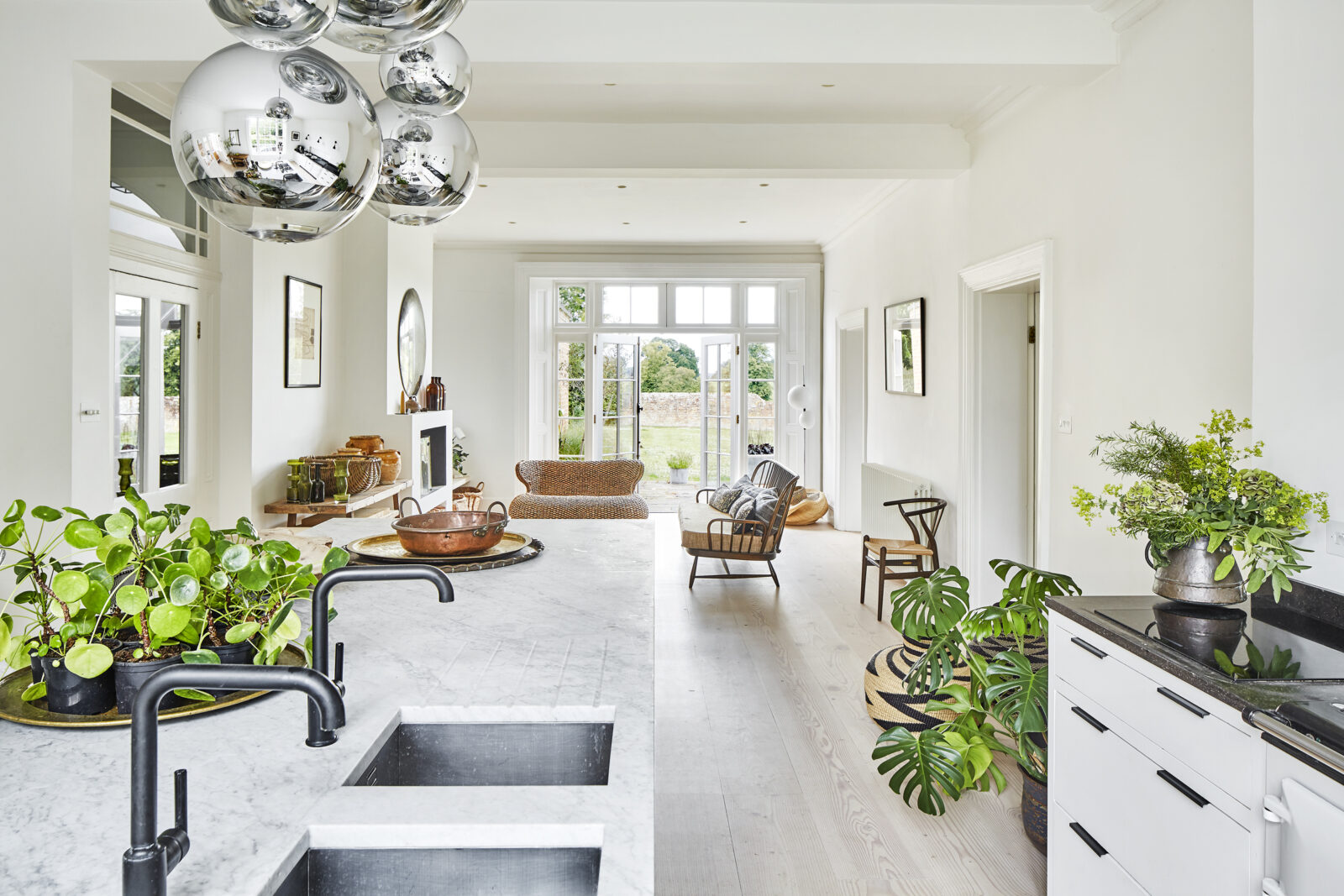 A white kitchen with lots of plants in it.