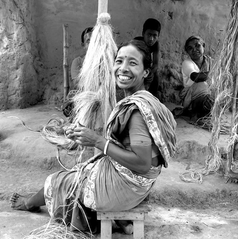 Black and white photo of a woman weaving a loom.