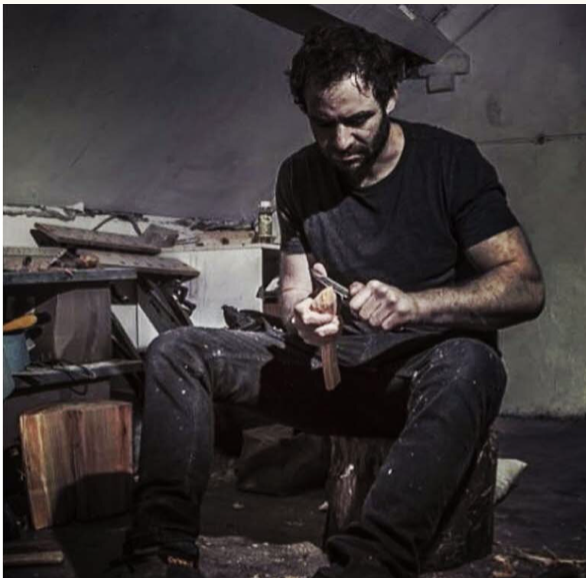 A man is working on a piece of wood in a workshop.