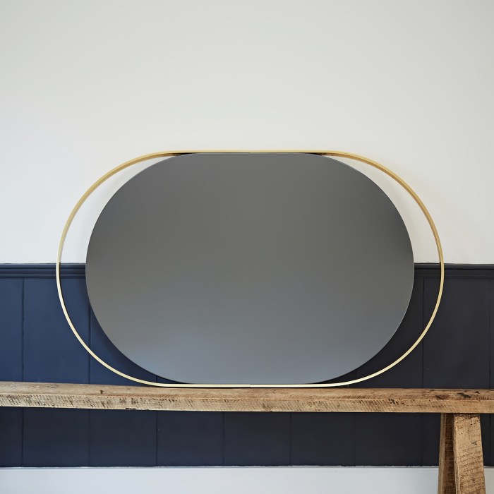 A 1970s Italian brass mirror on a wooden table next to a blue wall.