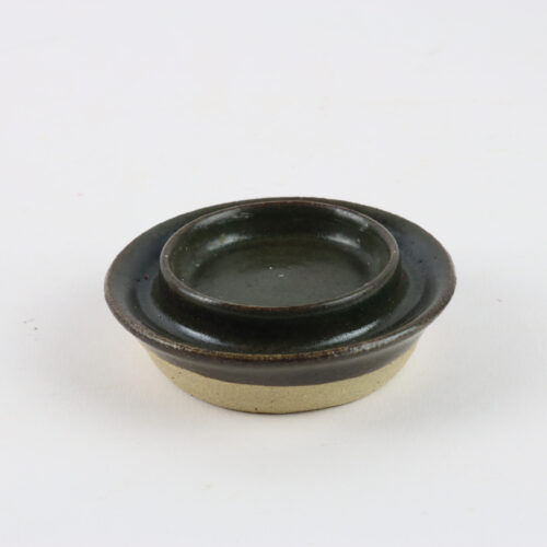 A small bowl with a lid on a white surface.